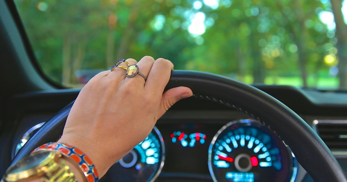 Mano con anillos sosteniendo la parte superior del volante