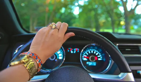 Hand with rings holding top of steering wheel