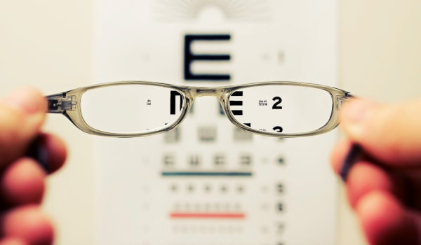 Holding glasses with eye chart in background