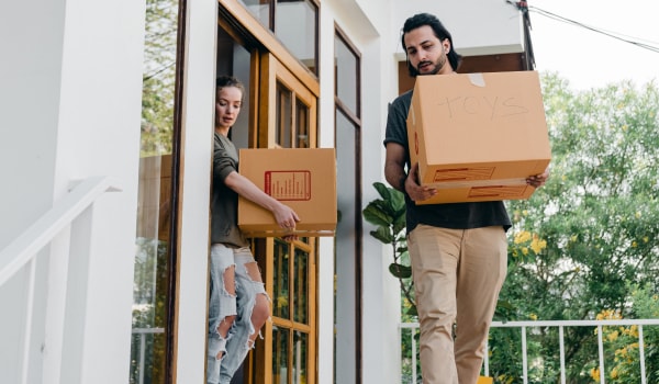 couple carrying boxes while moving out of home